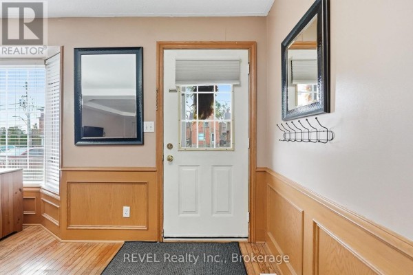 Interior hallway with a white door, wainscoting, and a mirror on the wall. - 3 Ormond Street N, Thorold