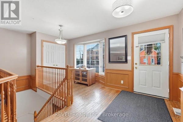 Interior hallway with a bay window, wooden staircase, and two doors. - 3 Ormond Street N, Thorold