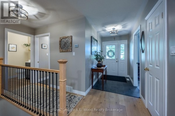 Interior hallway with light wood floors, grey walls, and a staircase with black spindles. - 3 Otterview Drive, Norwich