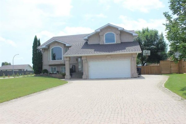 Garden shed with double doors, surrounded by grass and shrubs in the backyard. - 3 Parkwood Cove, Steinbach