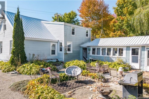 Backyard with patio furniture, grill, and landscaping with fall foliage in the background. - 3 Pleasant Street, St  Stephen