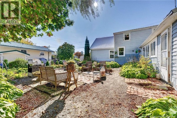 View of the backyard with brick and gravel patio areas, seating, and outdoor appliances. - 3 Pleasant Street, St  Stephen