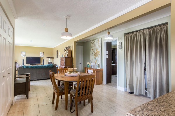 Dining area with a wooden table and chairs, adjacent to the living room and kitchen entrance. - 3 Rue Aldège-clément, Gatineau