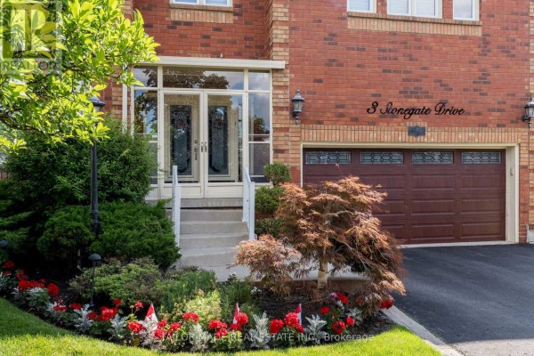 View of the front door and garage door on a brick house, with decorative landscaping. - 3 Stonegate Drive, Brampton