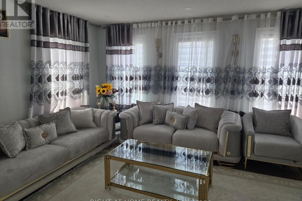 Living room with grey sofas, a gold coffee table, and decorative curtains. - 3 Wainwright Drive, Ajax