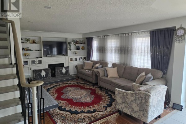Family room with sofas, built-in entertainment unit, fireplace, and large rug. - 3 Wainwright Drive, Ajax