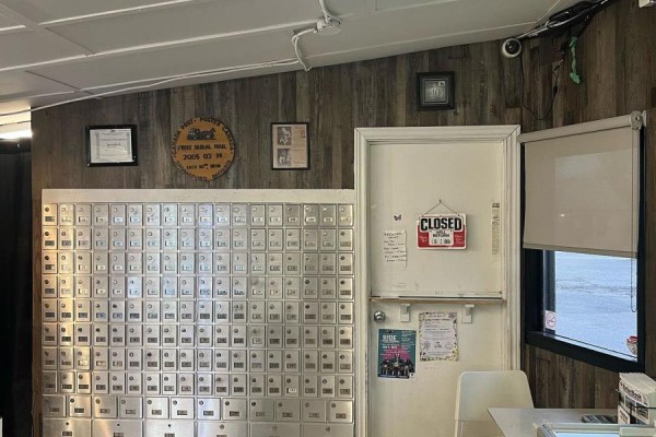 Interior wall with rows of mailboxes, a closed sign on a door, and wood-paneled walls. - 3 West Street N, Norwich