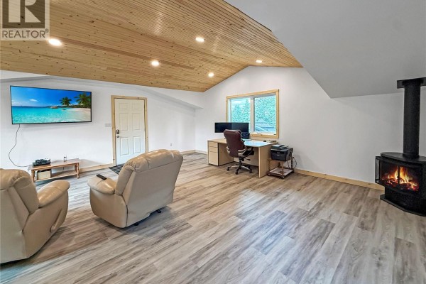 Spacious room with a wood-paneled ceiling, fireplace, and leather furniture. - 3 White Spruce Crescent, Candle Lake