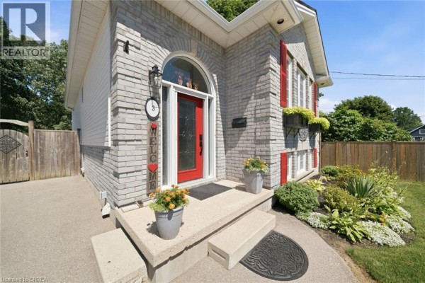 Close-up of the front entrance of the bungalow, featuring a red door, steps, and landscaping. - 3 Wood Street, Brantford
