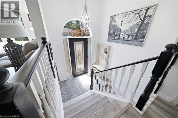View from the top of the staircase looking down at the entryway, showing a front door and artwork. - 3 Wood Street, Brantford