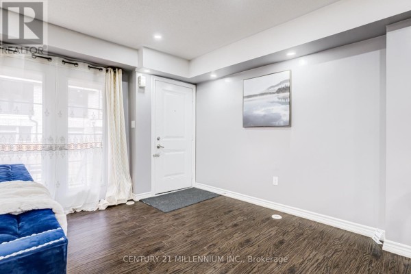 Bedroom with a bed featuring a patterned duvet, white doors, and a mounted TV. - 30 - 200 Veterans Drive, Brampton