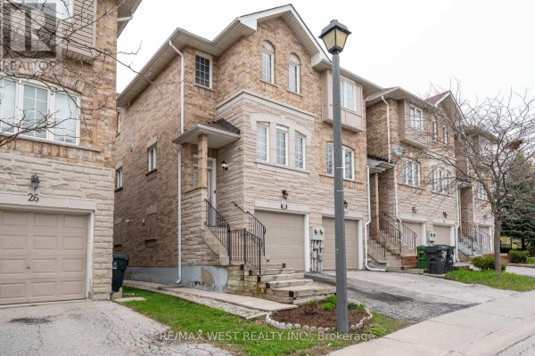 Close-up exterior view of a brick townhouse with an attached garage and driveway. - 28 Shining Star Crescent, Toronto