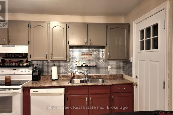 Kitchen with light brown cabinets, red lower cabinets, and beige backsplash. - 30 - 30 St Charles Place, Huron East