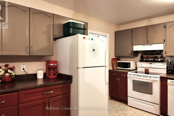 Kitchen with white refrigerator, white stove, and dark red lower cabinets. - 30 - 30 St Charles Place, Huron East