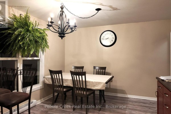 Dining room with a table set for four and a large hanging fern. - 30 - 30 St Charles Place, Huron East