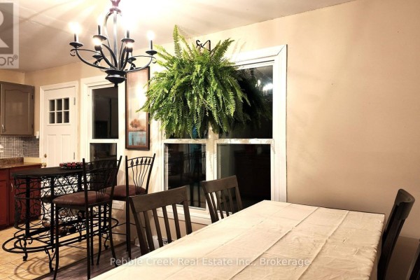 Dining area with a table, chairs, bar stools, and large windows. - 30 - 30 St Charles Place, Huron East