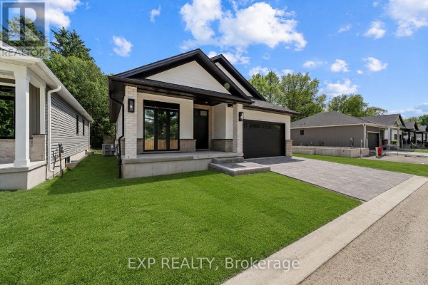 Side view of a modern white and grey house with a paved driveway and green lawn. - 30 - 430 Head Street N, Strathroy Caradoc