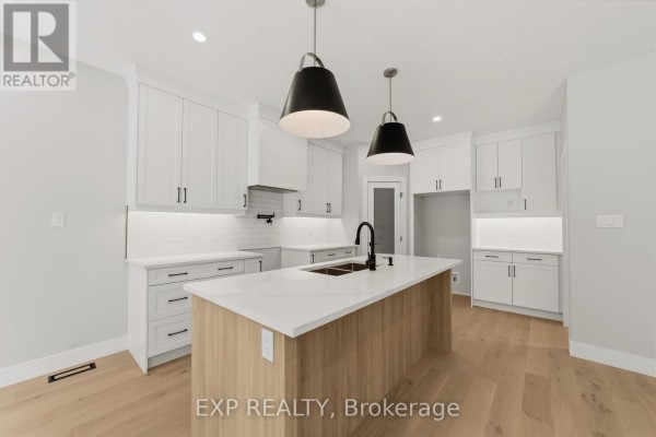 Bright white kitchen with a large island, light wood cabinets, and black hardware. - 30 - 430 Head Street N, Strathroy Caradoc