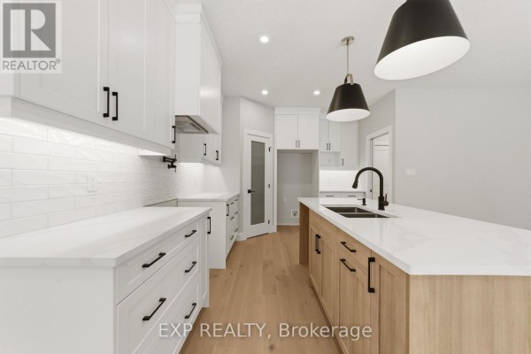 Spacious white kitchen with white subway tile backsplash, light wood island, and modern lighting. - 30 - 430 Head Street N, Strathroy Caradoc