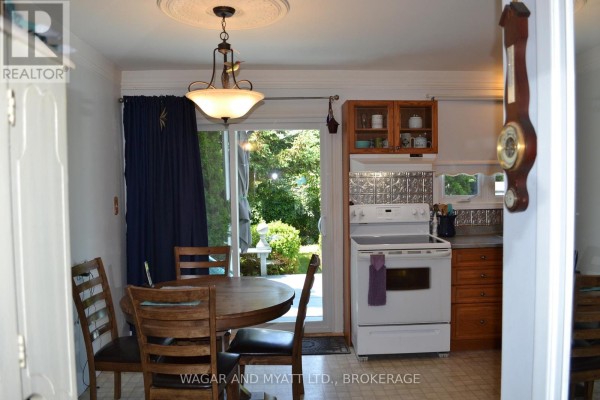 Kitchen area with a round wooden table and chairs, sliding glass doors, and a grandfather clock. - 30 - 60 Winchester Drive, Greater Napanee
