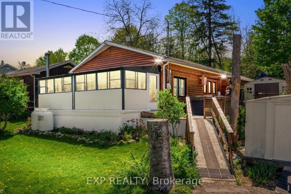 Side view of the home featuring a deck, lawn, and propane tank. - 30 - 6108 Curtis Point Road, Alnwick/haldimand