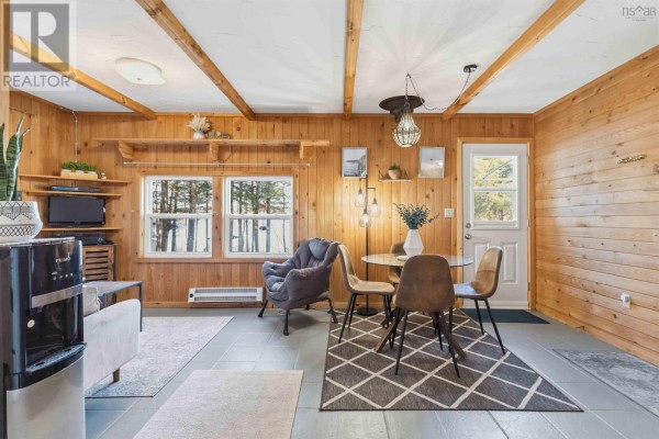 Interior living area with wood-paneled walls and ceiling, tile floor, and furniture including chairs and a table. - 30 11-15 Road, Hibernia