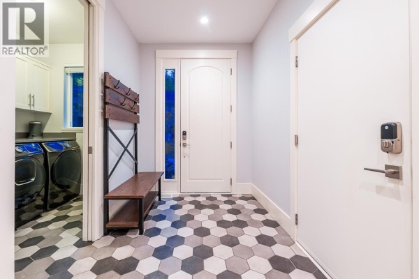 Entryway with hexagonal tile floor, white doors, and laundry room entrance. - 30 3295 Sunnyside Road, Anmore