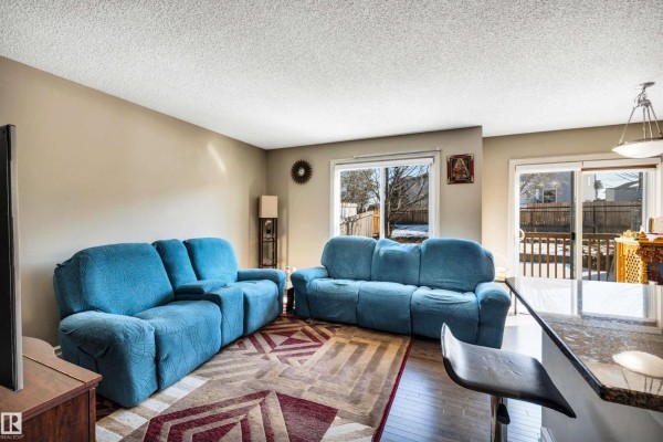 Entrance hallway with dark hardwood floors, beige walls, white doors, and a staircase leading upstairs. - #30 655 Tamarack Rd Nw, Edmonton