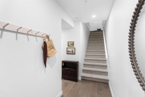 Interior entryway with white walls, gray carpeted stairs leading up, and a wooden floor. - 30 9122 King Street, Langley