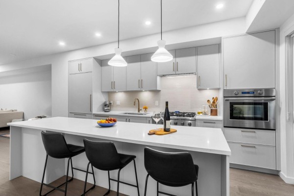 Modern gray kitchen with a large island, stainless steel appliances, and pendant lights. - 30 9122 King Street, Langley