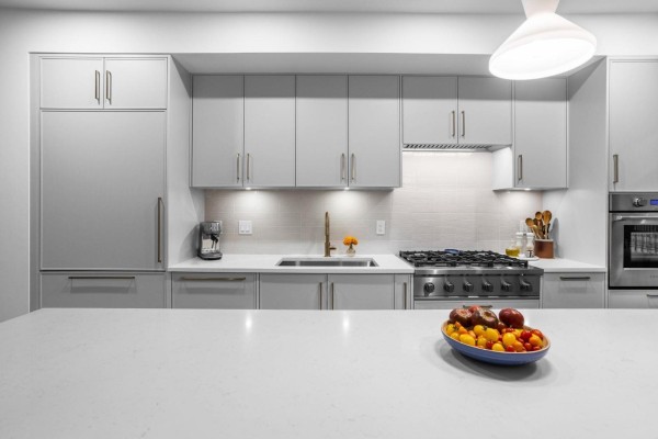 Gray kitchen with white quartz island, stainless steel oven, gas stove, and sink. - 30 9122 King Street, Langley