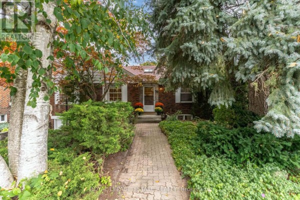 View of the house from the end of a paved walkway lined with mature trees and shrubs. - 30 Barbara Crescent, Toronto