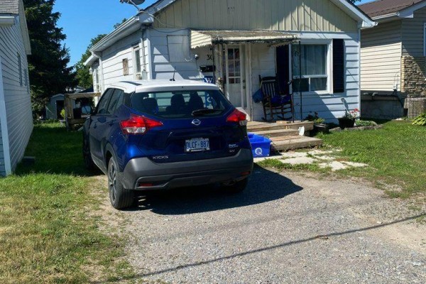Close-up of the front of the house showing the driveway and a blue SUV. - 30 Bocage Street, Quinte West
