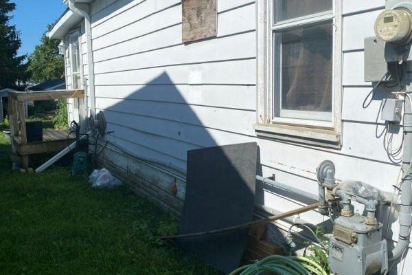 Side exterior of the house showing white vinyl siding, a window, and utilities. - 30 Bocage Street, Quinte West
