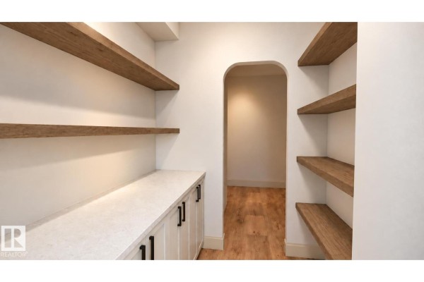 A walk-in pantry with ample shelving, a countertop, and an arched doorway leading to another room. - 30 Brickyard Vw, Stony Plain
