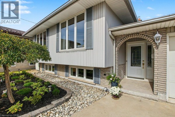 Close-up of the house entrance, featuring a brick archway, front door, and decorative landscaping. - 30 Catalina Drive, Hamilton