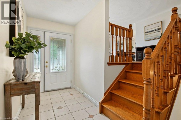 Interior view of the foyer with a wooden staircase, tiled floor, and entryway table. - 30 Catalina Drive, Hamilton