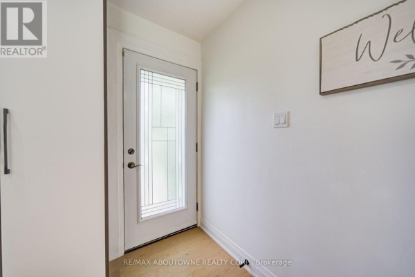 Interior view of a bright entryway with a glass-paned door and white walls. - 30 Dale Avenue, Hamilton