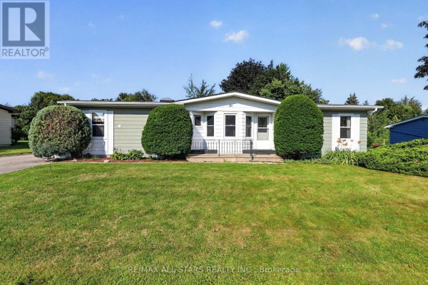 Front exterior of a light blue single-story house with green trim and manicured bushes. - 30 Damsel Circle, Georgina