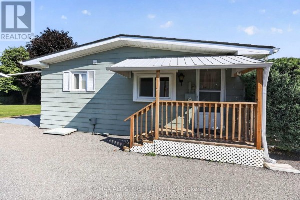 Side entrance of a light blue house with a wooden porch, railings, and white lattice skirting. - 30 Damsel Circle, Georgina