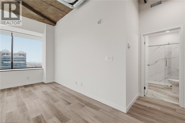 Modern kitchen with dark wood cabinetry, stainless steel appliances, and white countertops. - 30 Duke Street W Unit# 315, Kitchener