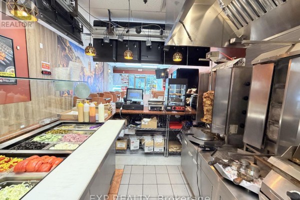 Food service counter with salad bar, shawarma grill, and cash register in a commercial kitchen. - 30 Eglinton Avenue W, Mississauga