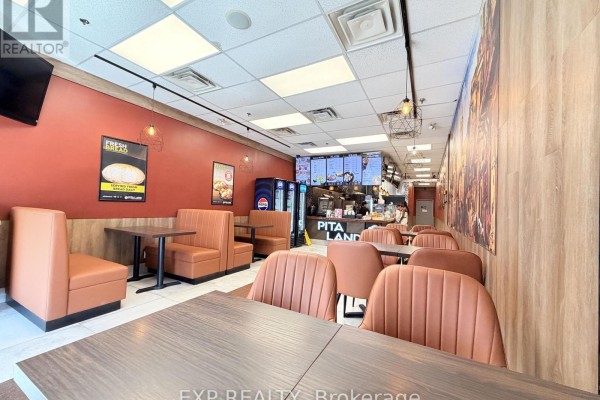 Restaurant dining area with orange booths, wooden tables, and chairs against wood-paneled walls. - 30 Eglinton Avenue W, Mississauga
