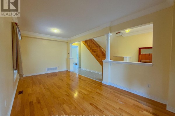 Living room with light yellow walls, hardwood floors, and view of staircase. - 30 Emery Hill Boulevard, Markham