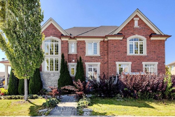 Side exterior of a red brick house with large windows, stone accents, and mature landscaping. - 30 Fairmont Ridge Trail, King
