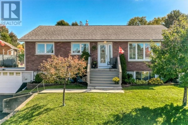 Front view of the brick house at 30 Fir St with a sloped lawn and trees. - 30 Fir St, Onaping