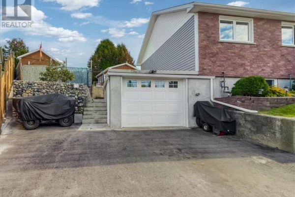 Rear exterior of the house showing a white garage door, asphalt driveway and steps. - 30 Fir St, Onaping