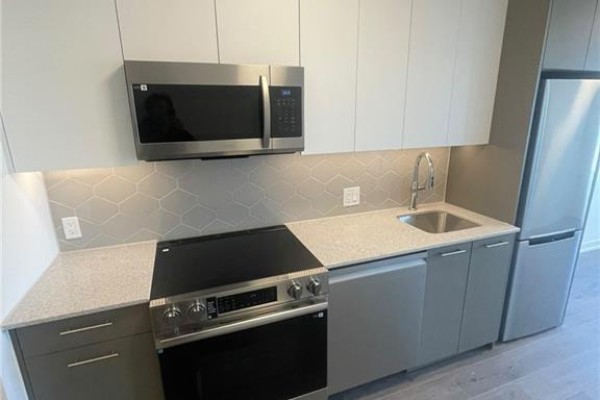 Close-up of a modern kitchen featuring stainless steel appliances, sink, and light grey cabinetry. - 30 Francis Street S Unit# 207, Kitchener