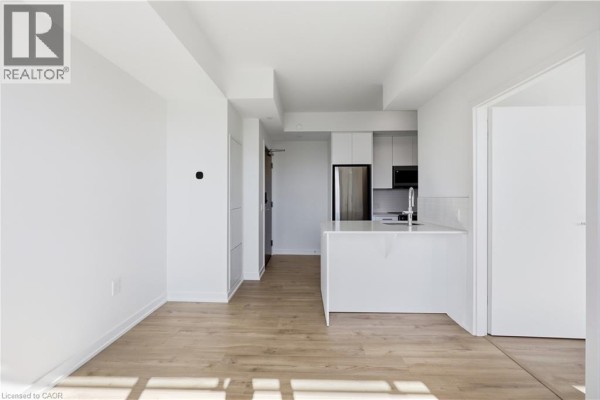 Living room space with view of white kitchen island and entrance. - 30 Francis Street S Unit# 602, Kitchener