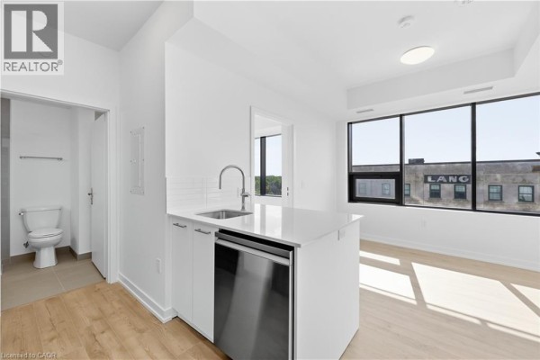 Kitchen island with sink, dishwasher, and view of large window. - 30 Francis Street S Unit# 602, Kitchener